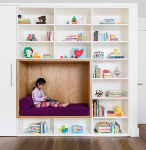 Kamar dengan dinding penuh buku dan sudut membaca yang nyaman